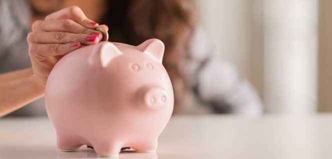 Woman Putting Coin In Piggy Bank